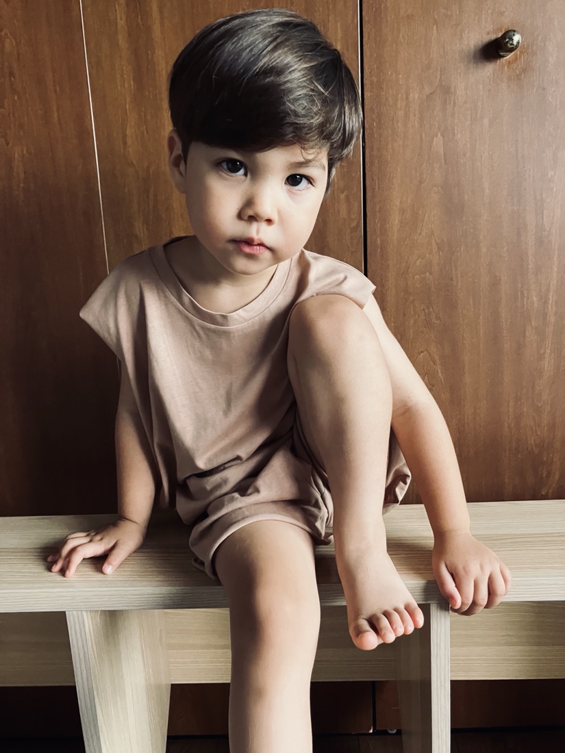 Child sitting on a bench in A Basic Brand clothing